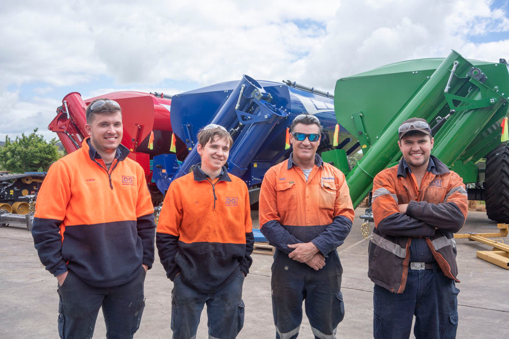 Four Davimac employees sanding in front of three red, blue and green chaser bins