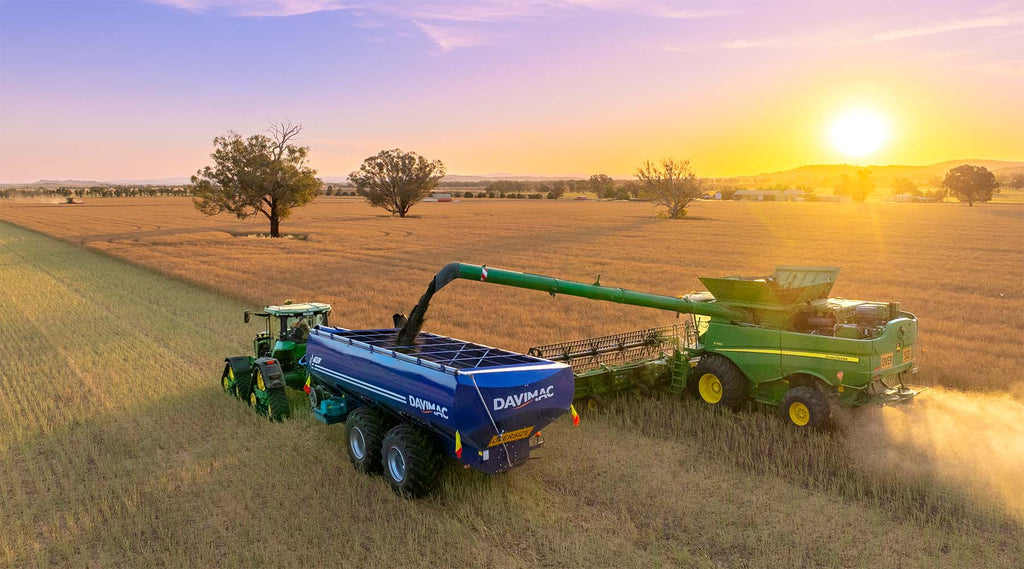 Davimac Dual Axle Chaser Bin with Green combine harvester and sunset in background