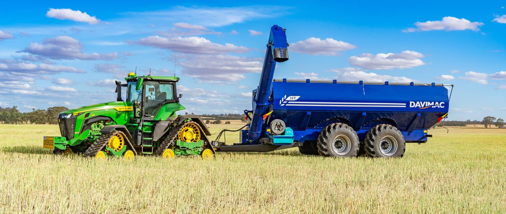 Davimac Chaser Bin Dual Axle in field with auger extended and green tractor